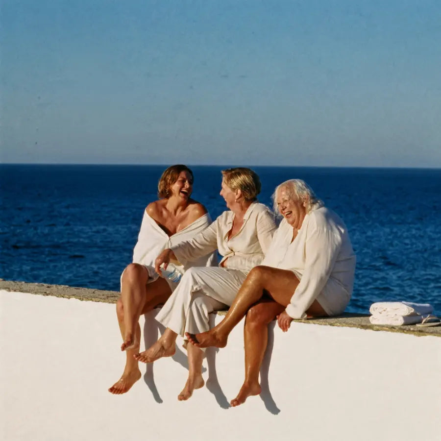 Trois amies de plus de 50 ans rient au bord de la mer